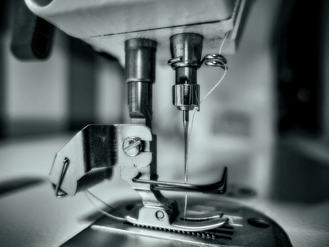 Black-and-white close-up of the needle of an industrial sewing machine
