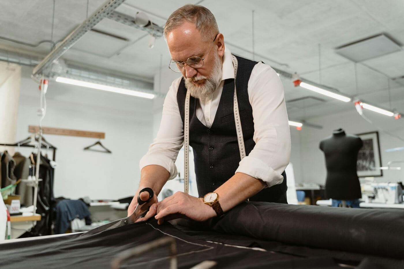 A tailor cutting dark fabric in his workshop